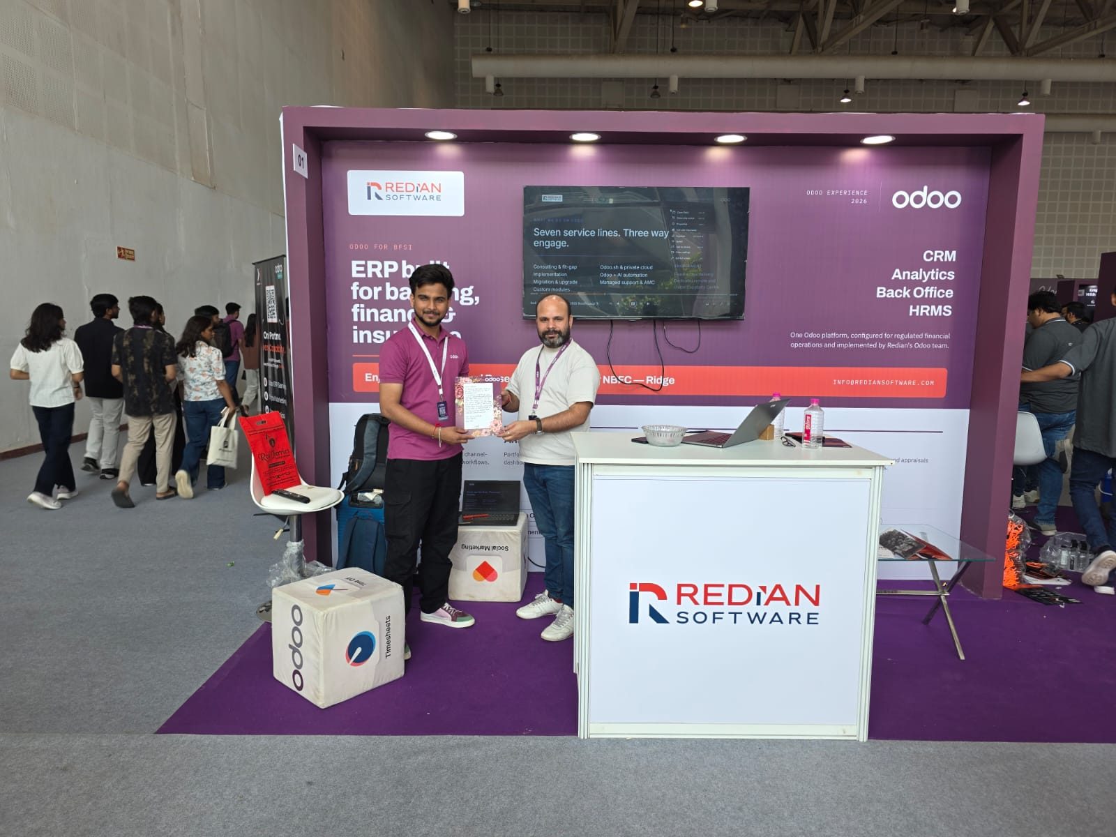 Redian booth in action — Pavan walking a visitor through the seven service lines on the demo screen